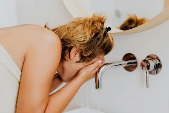 Woman washing her face with hard tap water.