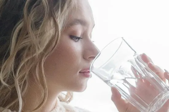 Girl drinking healthy tap water thanks to a water softener that saves energy and retains healthy minerals.